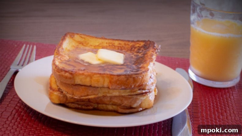 Dads Guide To Flawless French Toast 2 Two slices of perfectly cooked French toast, golden brown and fluffy, sitting on a white plate ready to be served.
