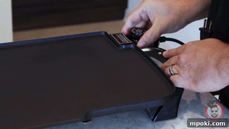 Dads Guide To Flawless French Toast 4 A close-up of a hand plugging in an electric griddle, preparing to make French toast.