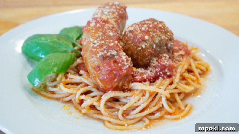 Instant Pot Italian Spaghetti: Weeknight Wonder 2 A generous serving of Instant Pot Spaghetti with Italian Sauce, complete with tender meatballs and succulent sausage, garnished with fresh basil on a white plate.