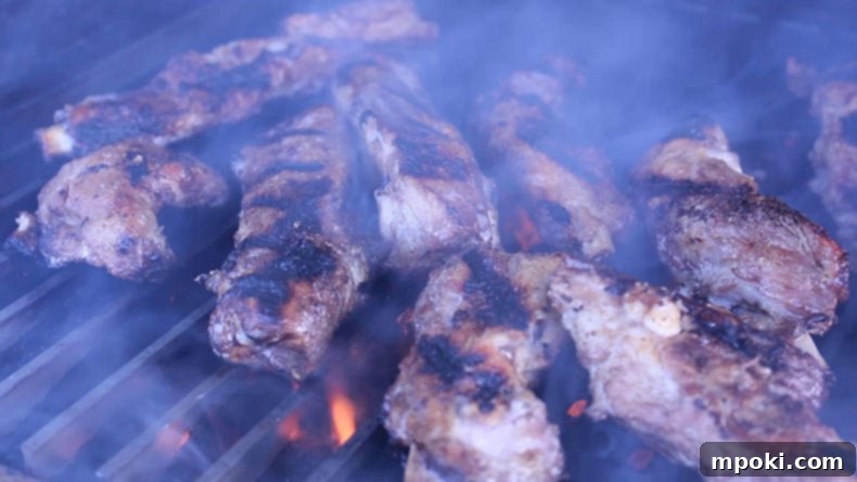 Sous Vide Spare Ribs: 12 or 24 Hours, Always Perfect 5 Ribs smoking on a grill with flames, showcasing a crispy, caramelized crust being formed.