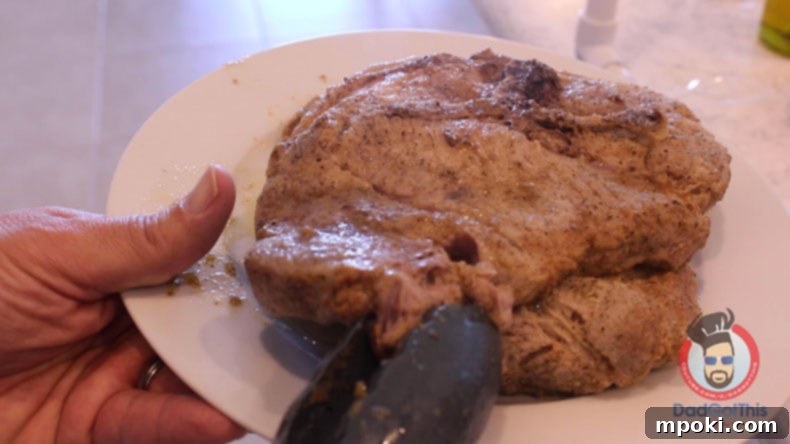 Delicious Instant Pot Pork Bistek Tagalog 6 A pork blade steak being pulled apart by tongs on a white plate