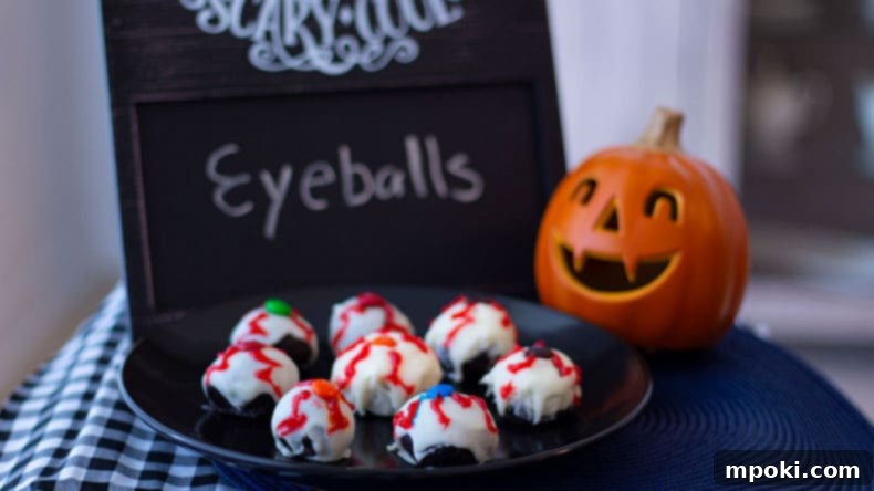 Spooktacular Oreo Truffles: Easy, Cheap, and Delicious 2 Oreo eyeball truffles on a black plate with a pumpkin next to it, perfect for Halloween treats.