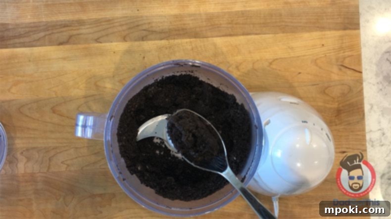 Spooktacular Oreo Truffles: Easy, Cheap, and Delicious 4 Oreo cookies being crushed into crumbs in a food processor with a spoon.