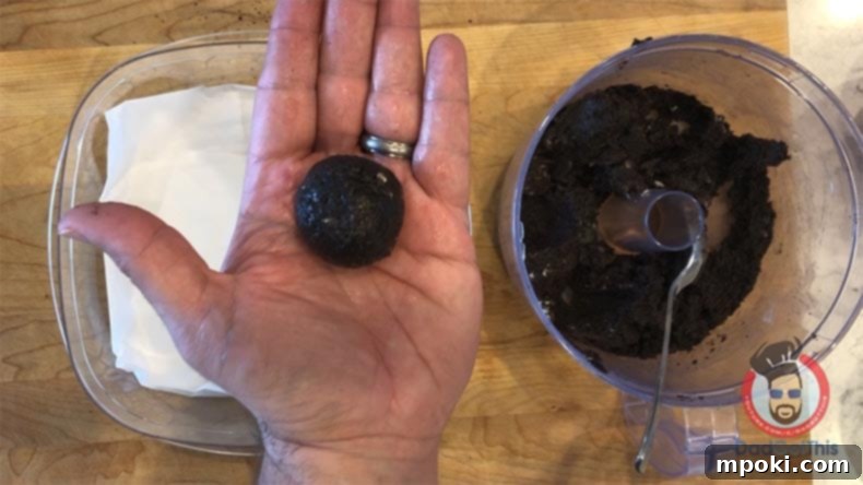 Spooktacular Oreo Truffles: Easy, Cheap, and Delicious 7 A hand rolling Oreo truffle dough into a ball, ready to become a spooky eyeball treat.