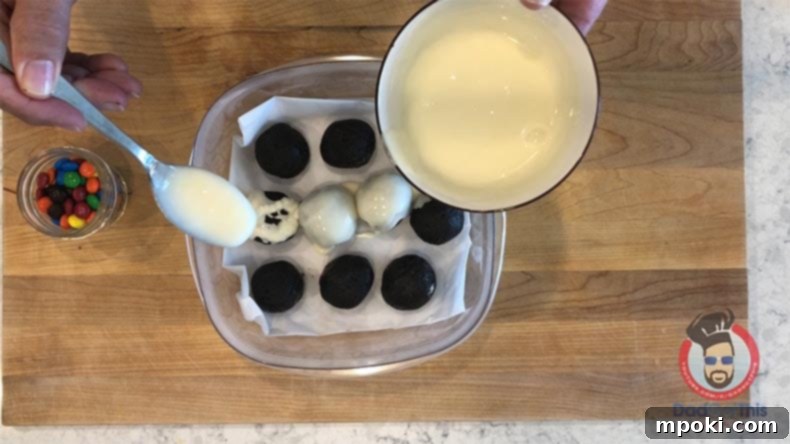 Spooktacular Oreo Truffles: Easy, Cheap, and Delicious 8 A spoon pouring melted vanilla frosting over chilled Oreo truffles to create white eyeballs.