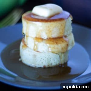 Dad Makes Amazing Japanese Pancakes 10 Three perfectly stacked, fluffy Japanese pancakes on a black plate, ready to be served.