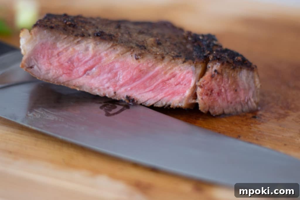 Unlocking Steak Perfection with Reverse Sear 2 A perfectly reverse seared steak, expertly cut on a wooden cutting board, revealing a tender, juicy interior, accompanied by a sharp knife.