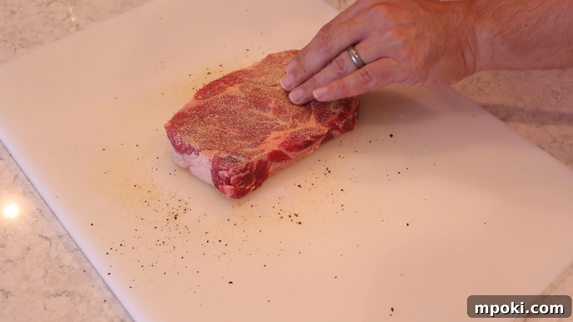 Unlocking Steak Perfection with Reverse Sear 4 A thick ribeye steak generously seasoned with a blend of garlic powder, onion powder, black pepper, and sea salt, ready for cooking.