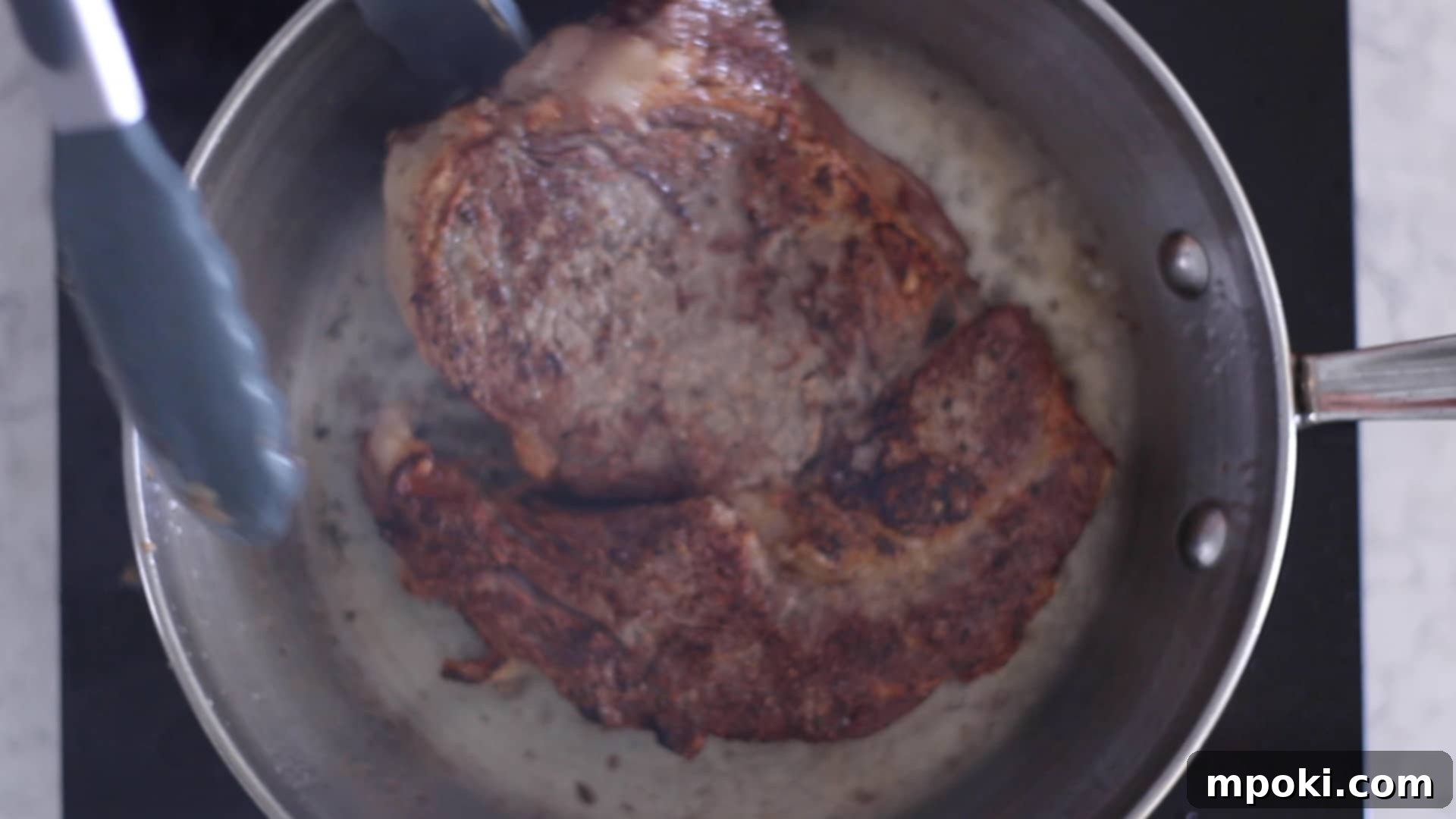 Unlocking Steak Perfection with Reverse Sear 6 A sizzling steak being expertly seared in a hot cast iron pan, showing a developing brown crust and the addition of butter for basting.