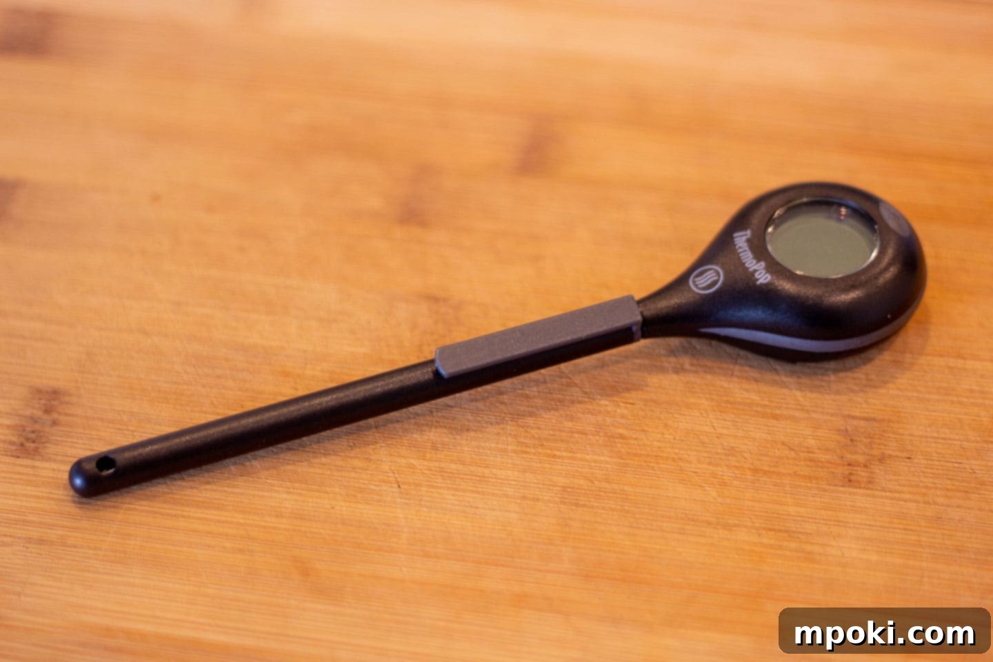 Unlocking Steak Perfection with Reverse Sear 8 A high-quality digital meat thermometer resting on a cutting board next to a cooked steak, emphasizing the importance of accurate temperature.