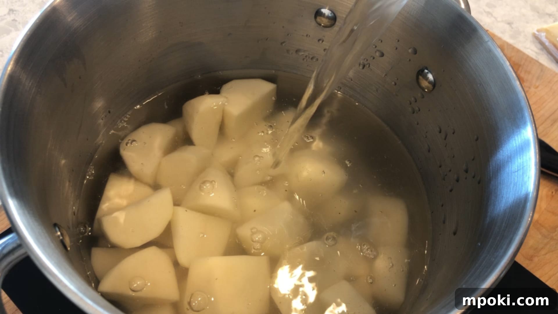 Mickey's Creamy Parmesan Mashed Potatoes 5 Cut potatoes submerged in cold water in a large stainless steel pot on a stovetop