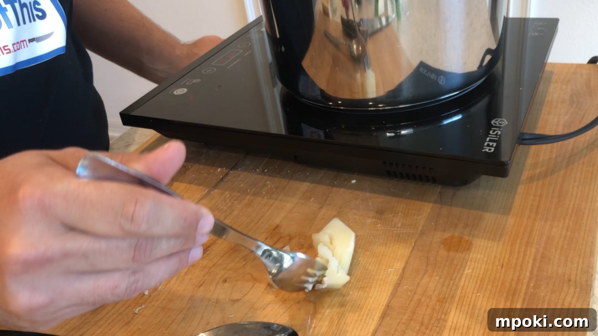 Mickey's Creamy Parmesan Mashed Potatoes 6 A hand testing a cooked potato chunk with a fork in a pot, demonstrating doneness