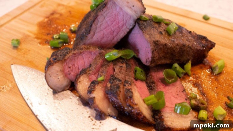 Charcoal Kissed Sous Vide Picanha 2 A sliced medium rare picanha steak on a wooden cutting board with a knife, ready to be served.