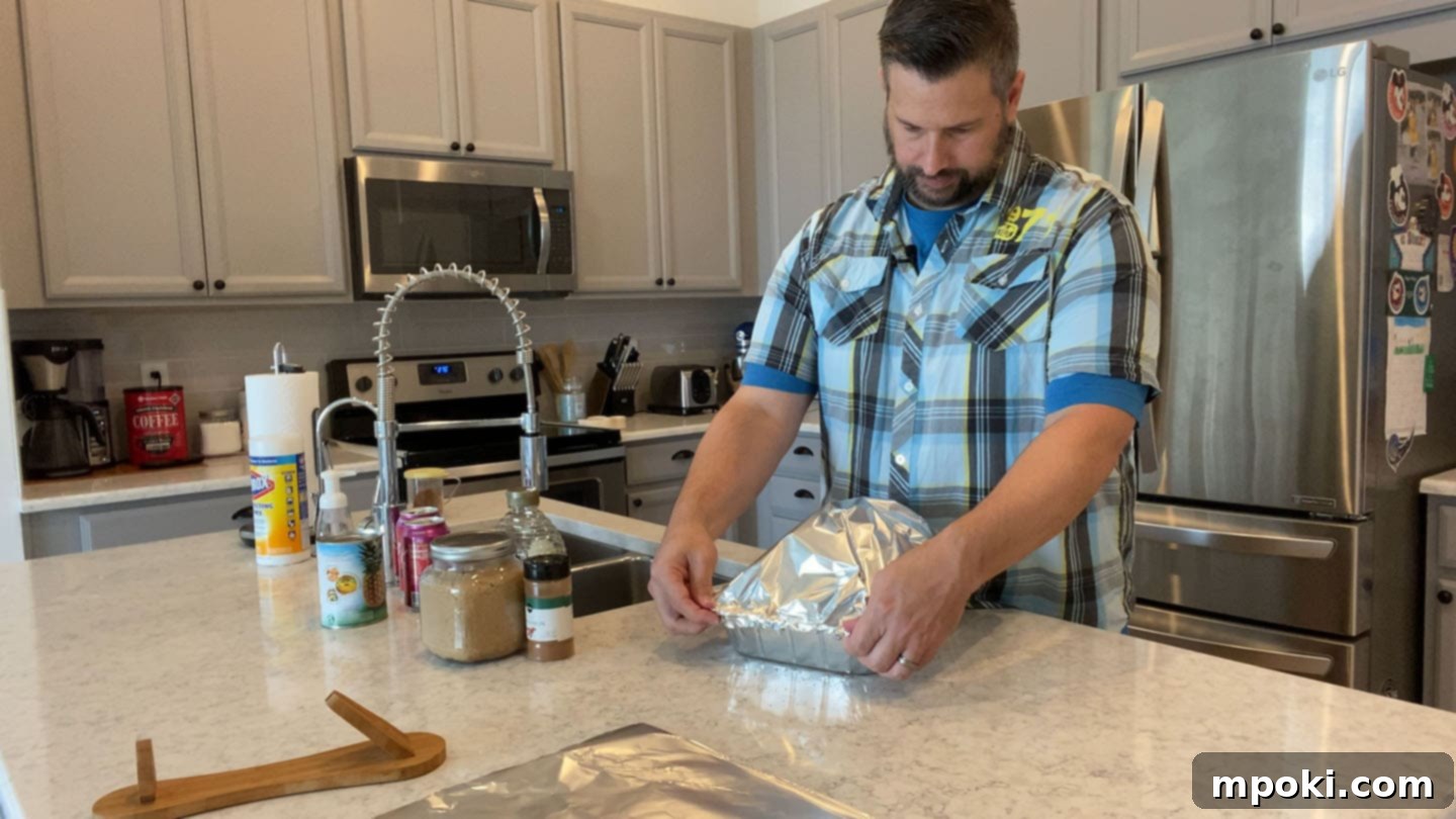 Decadent Honey Brown Sugar Glazed Spiral Ham 4 A large spiral sliced ham, perfectly tented with aluminum foil in a roasting pan, ready for slow warming in the oven.