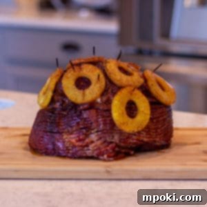 Decadent Honey Brown Sugar Glazed Spiral Ham 6 A beautifully caramelized pineapple-topped spiral sliced ham on a counter, ready to be served.