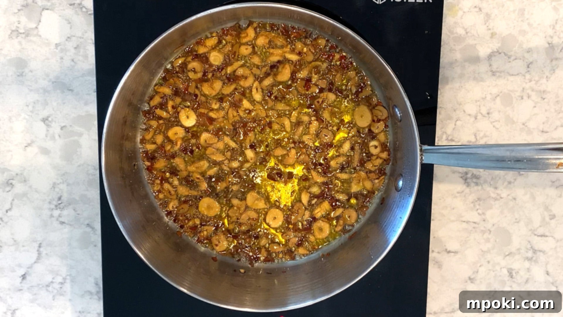 Sizzling Garlic Chili Pasta 5 Red pepper flakes added to garlic and oil in a pan, changing oil color