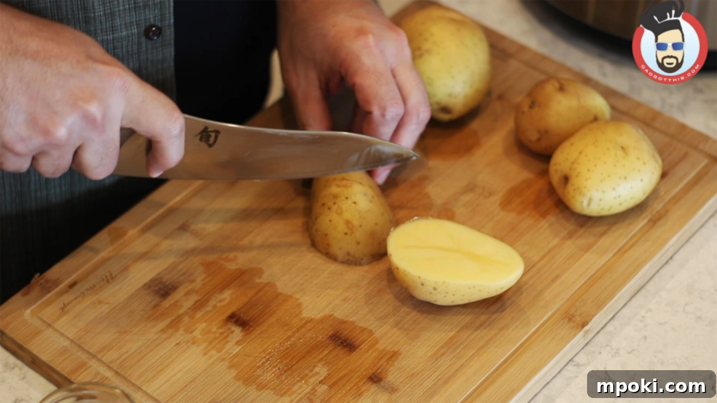Hearty Instant Pot Zuppa Toscana 3 Hands demonstrating chopping russet potatoes into uniform chunks on a wooden cutting board for Zuppa Toscana.