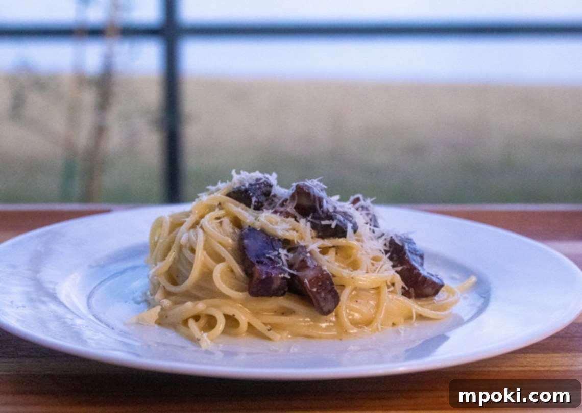 Rustic Wood-Fired Carbonara 2 Delicious Woodfire Carbonara served in a bowl, garnished with freshly ground black pepper and grated cheese.