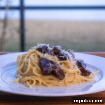Rustic Wood-Fired Carbonara 3 Close-up of Woodfire Carbonara with smoked guanciale and grated cheese.
